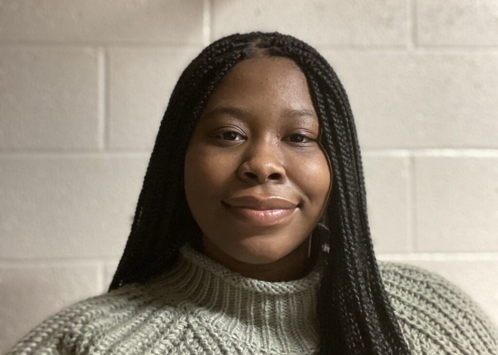 This picture is of Shaniya Longino as she wears Black individual braids and a green sweater. 